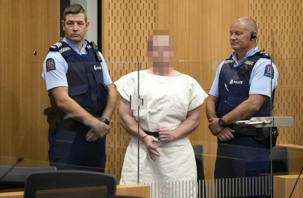 TOPSHOT - Brenton Tarrant, the man charged in relation to the Christchurch massacre,  makes a sign to the camera during his appearance in the Christchurch District Court on March 16, 2019. - A right-wing extremist who filmed himself rampaging through two mosques in the quiet New Zealand city of Christchurch killing 49 worshippers appeared in court on a murder charge March 16, 2019. Australian-born 28-year-old Brenton Tarrant appeared in the dock wearing handcuffs and a white prison shirt, sitting impassively as the judge read a single murder charge against him. A raft of further charges are expected. (Photo by Mark Mitchell / POOL / AFP) / EDS NOTE HIS FACE MUST BE PIXELATED..ONLY HIS FACE--