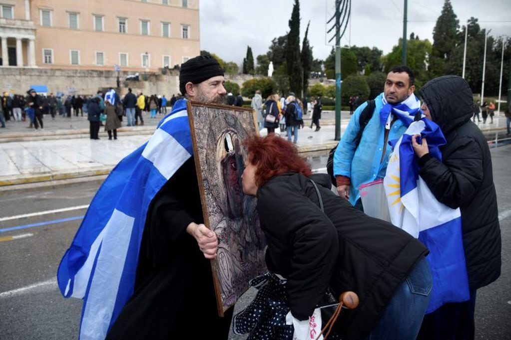 Una manifestante besa un ícono de la Virgen María sostenido por un monje ortodoxo griego durante la manifestación frente al edificio del Parlamento contra el acuerdo alcanzado por Grecia y Macedonia para resolver una disputa sobre el nombre de la ex república yugoslava