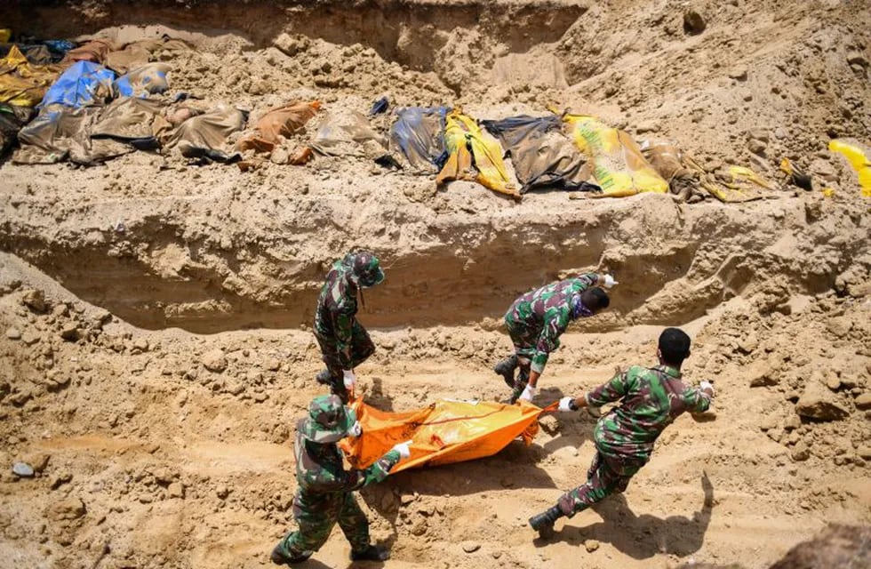 TOPSHOT - Indonesian soldiers bury quake victims in a mass grave in Poboya in Indonesia's Central Sulawesi on October 2, 2018, after an earthquake and tsunami hit the area on September 28. - The Indonesian government on October 2 said the death toll from a devastating quake-tsunami on the island of Sulawesi had risen to 1,234 people, up from the previous count of 844. (Photo by JEWEL SAMAD / AFP)
