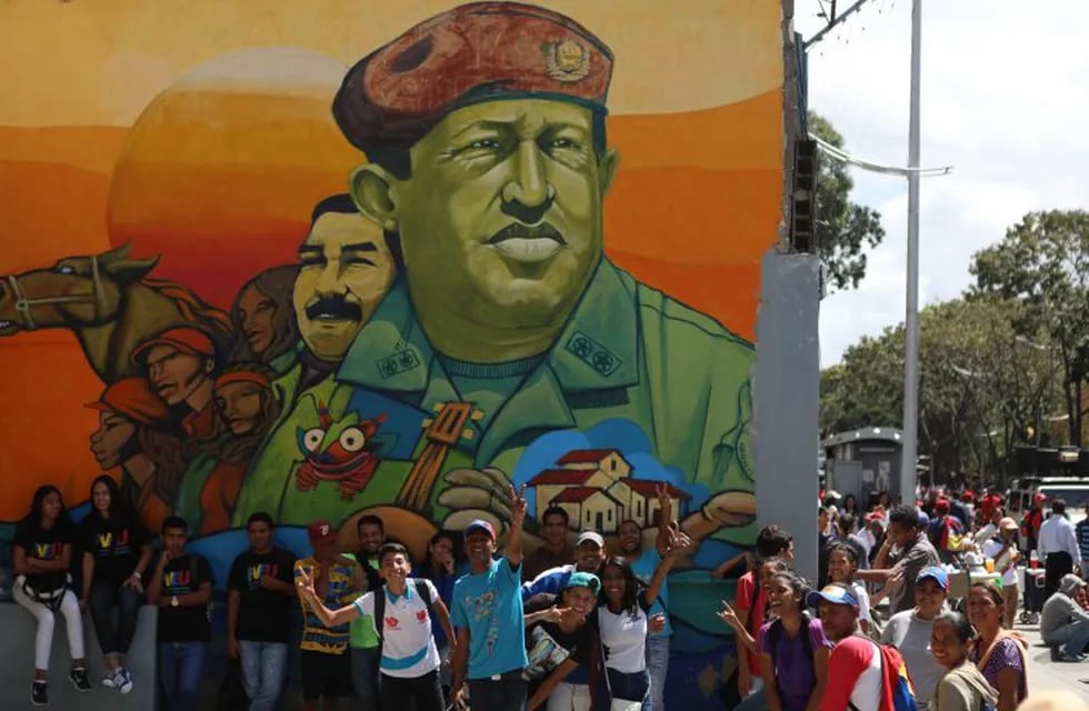 AME2209. CARACAS (VENEZUELA), 12/02/2019.- Un grupo de jóvenes posa junto a un mural del expresidente Hugo Chávez, durante una marcha en apoyo al gobierno del presidente de Venezuela, Nicolás Maduro, este martes, en Caracas (Venezuela). El presidente Nicolás Maduro, en el poder desde 2013, recibirá en el centro de Caracas a simpatizantes que marcharán para denunciar un presunto intento de golpe de Estado a su gestión y pedir que se respete la soberanía venezolana, que consideran amenazada por factores \