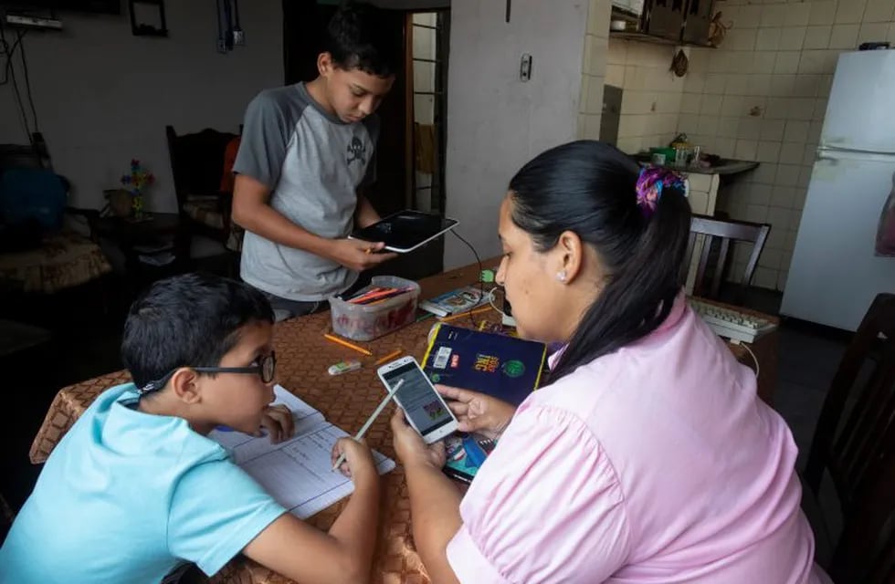 Leidy Martinez reads her son’s homework assignment on her cell phone, as her other son Joandry, 12, checks the internet connection in a tablet at their home in Las Mayas slum of Caracas, Venezuela, Thursday, May 7, 2020. Leidy's children, both with Asperger syndrome, get their schoolwork via WhatsApp or Facebook because schools are closed due to the lockdown to curb down the spread of the new coronavirus. (AP Photo/Ariana Cubillos)