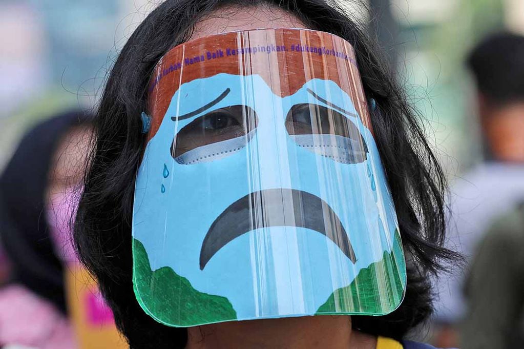Un activista con una máscara que representa una 'tierra llorando' asiste a una manifestación para conmemorar el Día de la Tierra en Yakarta, Indonesia, el jueves 22 de abril de 2021. Varios activistas organizaron la manifestación instando al gobierno indonesio a tomar medidas rápidas para abordar los problemas ambientales en el país.  (AP Photo/Tatan Syuflana)