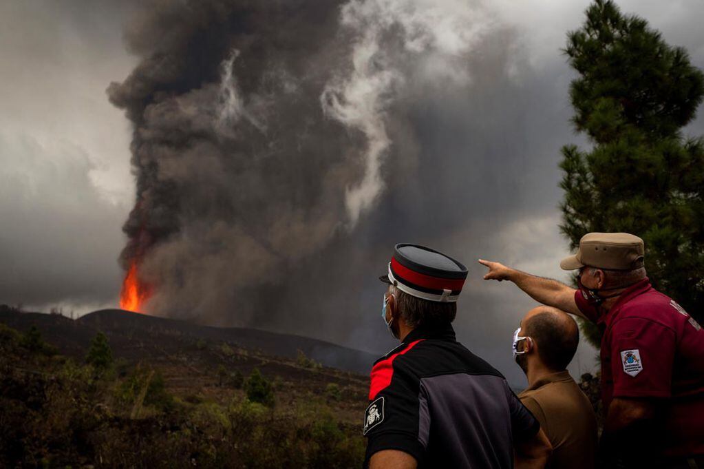 Agentes de policía y trabajadores municipales miran como fluye  la lava de la erupción de un volcán. (AP)