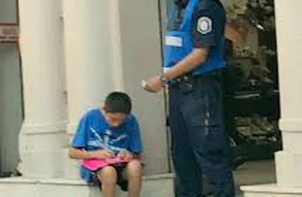 La historia detrás de la foto viral del policía ayudando a estudiar a un chico.