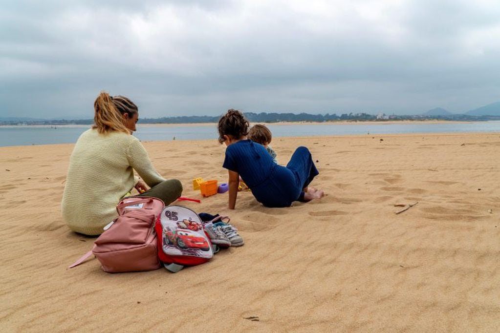 Una mujer observa cómo juegan sus hijos en la playa de los peligros en Santander, este domingo. (Foto: EFE/ Román G. Aguilera)