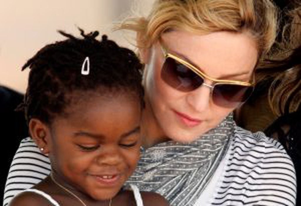 FILE PHOTO: Pop star Madonna sits with her adopted Malawian child Mercy James during a bricklaying ceremony at the site of her Raising Malawi Girls Academy, near the capital Lilongwe, Malawi, April 6, 2010.   REUTERS/Mike Hutchings/File Photo