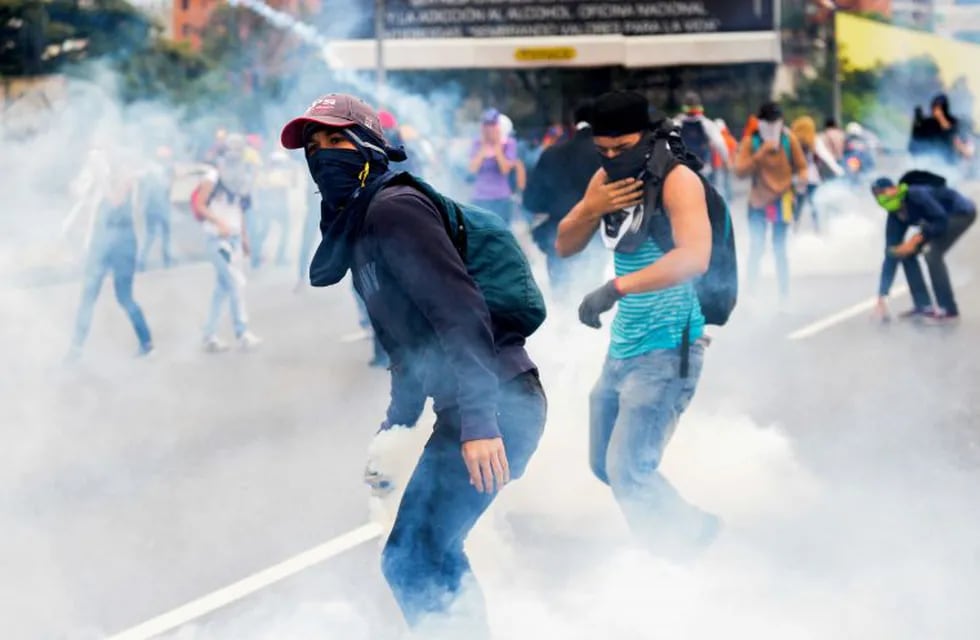 Venezuelan opposition activists clash with riot police during a protest against President Nicolas Maduro's government, in Caracas on April 13, 2017.nA 32-year-old man died Thursday after being shot and wounded in a demonstration on April 11, becoming the fifth victim in the protests that began almost two weeks ago. Dozens of people have been injured and more than 100 arrested since April 6, according to authorities. / AFP PHOTO / FEDERICO PARRA