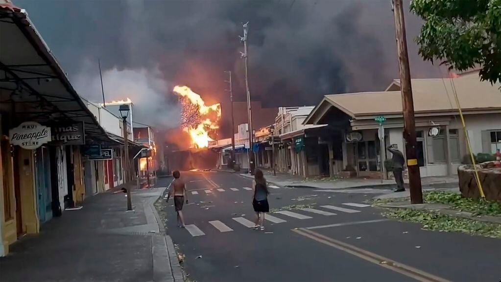 Varias personas observan mientras el humo y las llamas de los incendios forestales llegan a Front Street, en el centro de Lahaina, en Maui, Hawai, el 8 de agosto de 2023. (Alan Dickar vía AP)