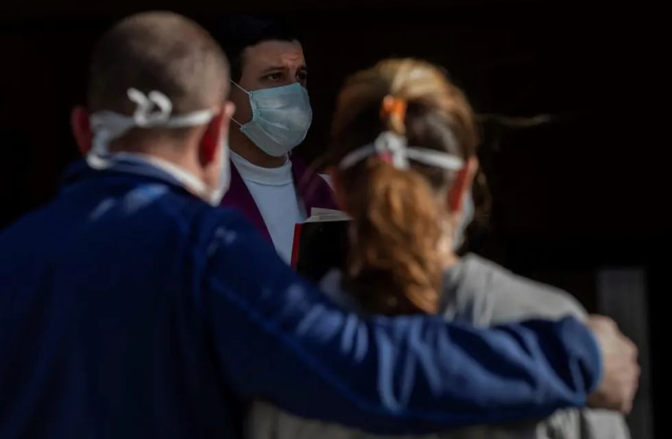 A priest wearing a face masks to protect against coronavirus performs funeral rites at a Madrid cemetery during the coronavirus outbreak in Madrid, Spain, Friday, March 27, 2020. The new coronavirus causes mild or moderate symptoms for most people, but for some, especially older adults and people with existing health problems, it can cause more severe illness or death. (AP Photo/Bernat Armangue)