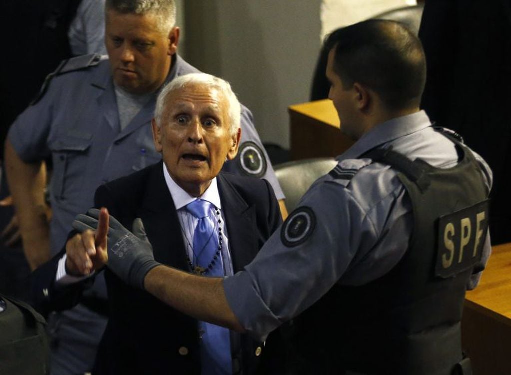 Miguel Etchecolatz (C) former Buenos Aires province's Chief of Police is taken away from a courtroom after hearing the verdict in the final stage of his trial for his role in the kidnapping, murder and torture of people during the Argentina's last dictatorship in the notorious clandestine detention centre known as La Cacha, in La Plata, Buenos Aires province October 24, 2104. REUTERS/Enrique Marcarian (ARGENTINA - Tags: CRIME LAW SOCIETY) la plata buenos aires miguel etchecolatz juicio oral delitos dictadura centro clandestino la cacha juicio acusados secuestros en la ultima dictadura militar acusados sentenciados