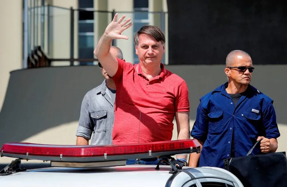 Brazilian President Jair Bolsonaro waves as he joins his supporters in a motorcade to protest against quarantine and social distancing measures to combat the new coronavirus outbreak in Brasilia on April 19, 2020. (Photo by Sergio LIMA / AFP)