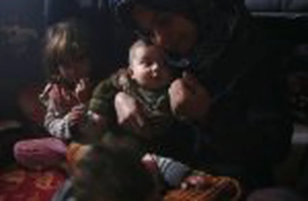 The mother (R) of Rasha al-Qassem (UNSEEN), who recently fled rebel-held Aleppo into the Syrian government held side, holds her grandchildren as the family reunites in their make-shift home in Syria's second city, on December 1, 2016.nRasha was among tens