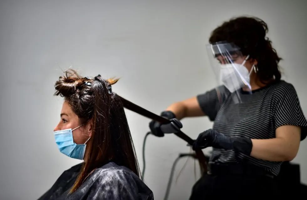 Andrea, 29 years old, is attended by hairstylist Laura Naturana in a hairdresser, Pamplona, northern Spain, Monday, May 4, 2020. Spaniards will be able to get a haircut, buy take away food as long as they have previously made an appointment and travel on public transport with mouth and nose covered with mandatory masks. (AP Photo/Alvaro Barrientos)