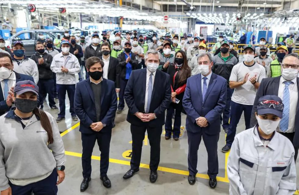 Handout photo released by Argentina's Presidency showing Argentine President Alberto Fernandez (C) and Buenos Aires province Governor Axel Kicillof (2nd L) posing with employees of Toyota production plant in Zarate, Buenos Aires, Argentina, on May 27, 2020 during the lockdown against the spread of the new coronavirus, COVID-19. (Photo by ESTEBAN COLLAZO / Argentinian Presidency / AFP) / RESTRICTED TO EDITORIAL USE - MANDATORY CREDIT \
