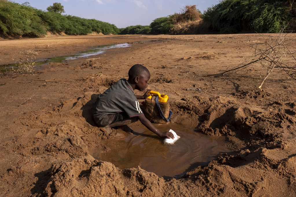 En Somalia, un niño trata de recoger agua de lo que queda de un río afectado por la sequía. 