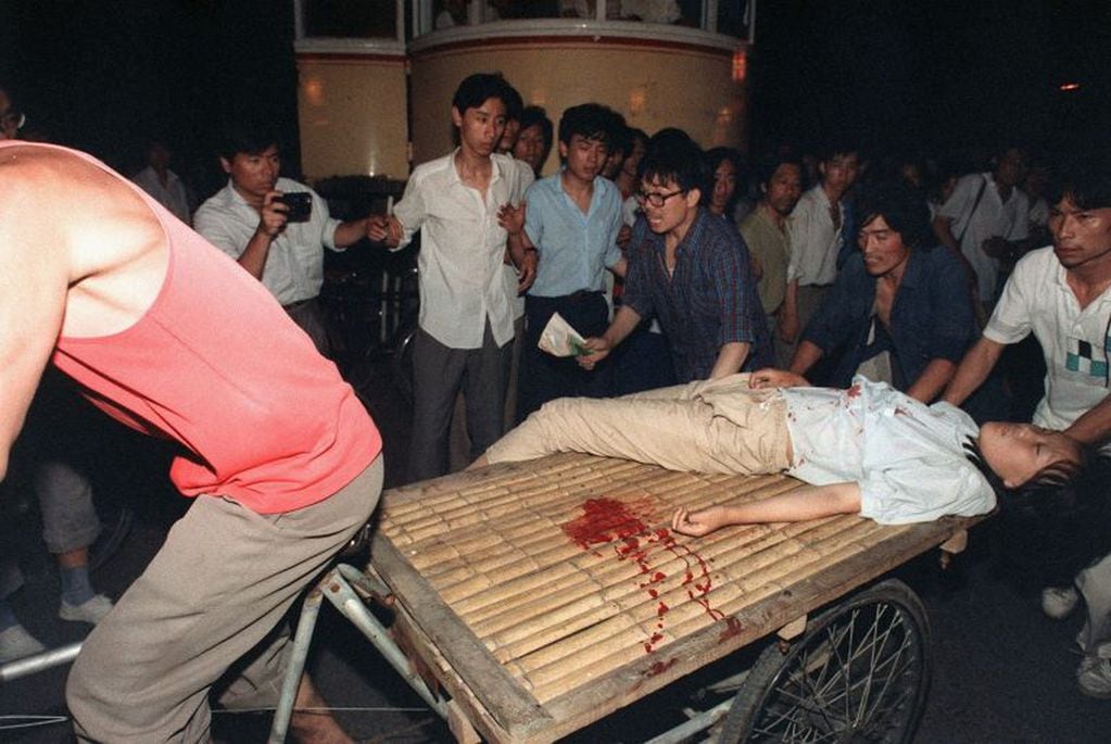 Esta foto de archivo, tomada el 4 de junio de 1989, muestra a una joven herida durante un enfrentamiento entre el ejército y estudiantes cerca de la Plaza de Tiananmen en Beijing, llevada en un carro.
  En junio de 1989, miles de personas murieron en la represión del ejército chino contra manifestantes a favor de la democracia en la Plaza de Tiananmen, según un cable diplomático secreto británico recientemente publicado que da detalles espantosos del derramamiento de sangre en Beijing. El documento, publicado más de 28 años después del evento, fue visto por AFP el 22 de diciembre de 2017 en los Archivos Nacionales de Gran Bretaña. / AFP FOTO / Manny CENETA