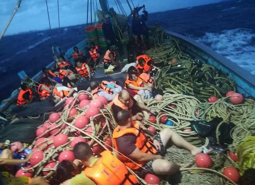 Varios turistas sentados en un barco pesquero tras ser rescatados cerca de la isla de Phuket.