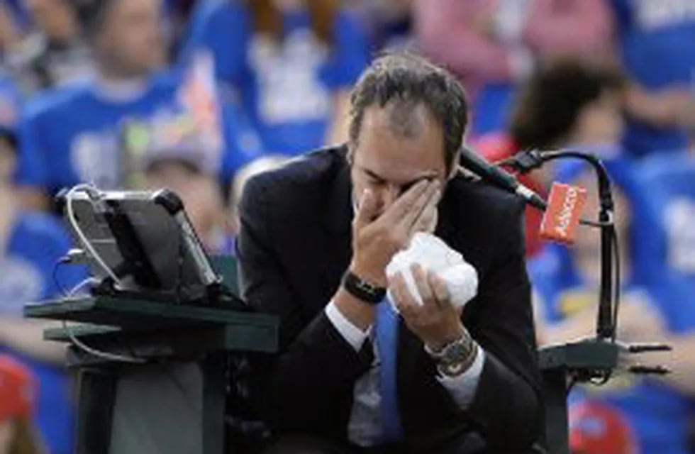Umpire Arnaud Gabas, of France, holds his face after being hit by a ball during first-round Davis Cup tennis match action between Canada's Denis Shapovalov and Britain's Kyle Edmund, Sunday, Feb. 5, 2017, in Ottawa, Ontario. (Justin Tang/The Canadian Pres