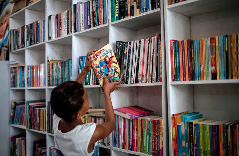 A boy places a book on a shelve of the public library Mundo da Lua (Lua's World), founded by Brazilian 12-year-old Lua Oliveira five months ago, at the Tabajaras favela in Rio de Janeiro, Brazil, on March 10, 2020. - Lua had the idea to open a public library after visiting the Rio de Janeiro International Book Fair last year and made posts in social networks asking for donations, which went viral. (Photo by MAURO PIMENTEL / AFP)