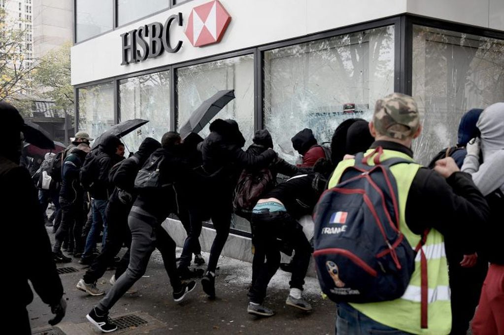 Los manifestantes rompen las ventanas de un banco HSBC cerca de la Porte d'Italie en París este viernes, durante una manifestación que conmemora el primer aniversario del movimiento del "chaleco amarillo". Crédito: Philippe LOPEZ / AFP.