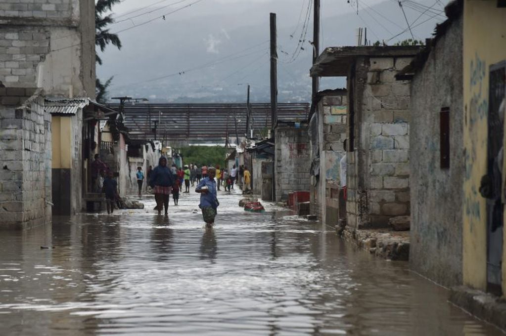 People are seen walking in flooded streets, in a neighbourhood of the commune of Cite Soleil, in the Haitian Capital Port-au-Prince, on October 4, 2016. 
Hurricane Matthew slammed into Haiti, triggering floods and forcing thousands to flee the path of a s