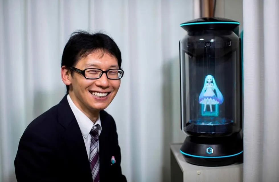 In this photograph taken on November 10, 2018 Japanese Akihiko Kondo poses next to a hologram of Japanese virtual reality singer Hatsune Miku at his apartment in Tokyo, a week after marrying her. - Akihiko Kondo, who is an administrator at a school, married to a Japanese virtual reality singer called Hatsune Miku in early November 2018. The bride is a computer animation with saucer eyes and lengthy aquamarine pigtails who performs to adoring fans as a hologram. (Photo by Behrouz MEHRI / AFP) / TO GO WITH AFP STORY: Japan-culture-entertainment-computers-music-social, FOCUS by Miwa SUZUKI tokio japon Akihiko Kondo No quiere una relación con una mujer real japones se caso con la famosa holograma Hatsune Miku esposo de la exitosa cantante de realidad virtual