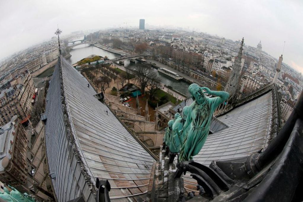 (FILES) A file photo taken on November 30, 2012 shows the statue of Viollet le Duc, the architect and restorer of the Notre-Dame de Paris cathedral in the 19th century, and the roof of the cathedral . - A huge fire swept through the roof of the famed Notre-Dame Cathedral in central Paris on April 15, 2019, sending flames and huge clouds of grey smoke billowing into the sky. The flames and smoke plumed from the spire and roof of the gothic cathedral, visited by millions of people a year. A spokesman for the cathedral told AFP that the wooden structure supporting the roof was being gutted by the blaze. (Photo by PATRICK KOVARIK / AFP)