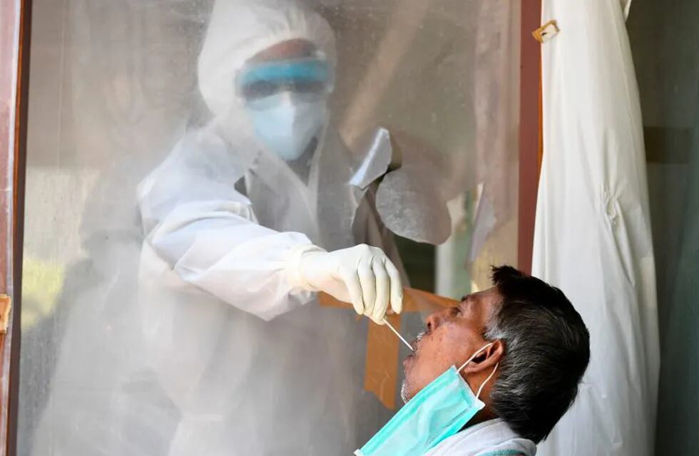 A health official collects a swab sample from a man to test for the COVID-19 coronavirus after authorities eased restrictions imposed as a preventive measure against the spread of the COVID-19 coronavirus, in New Delhi on June 16, 2020. (Photo by Sajjad  HUSSAIN / AFP)