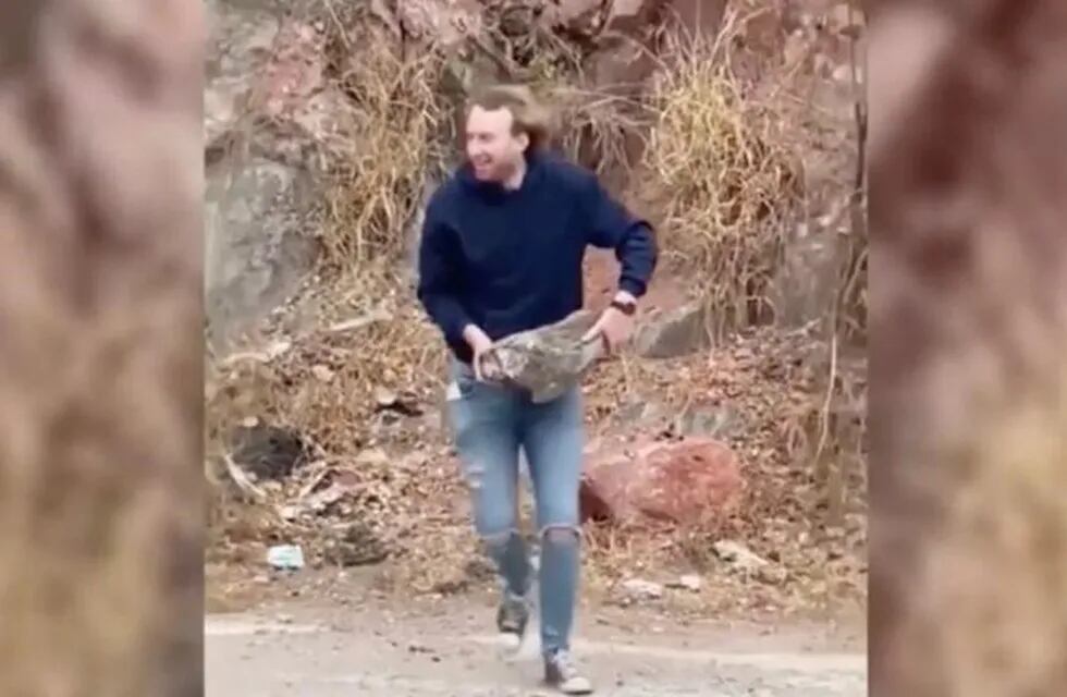 Imagen de un joven tirando una piedra de gran tamaño al embudo del Dique San Roque.