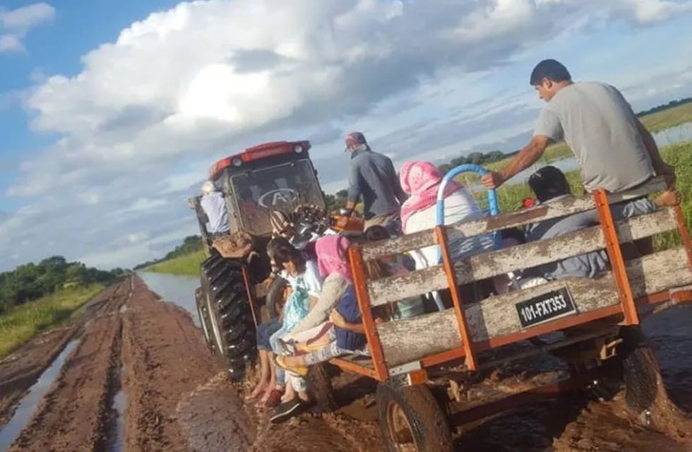 Un tractor lleva evacuados por los caminos destruidos a causa de las lluvias.