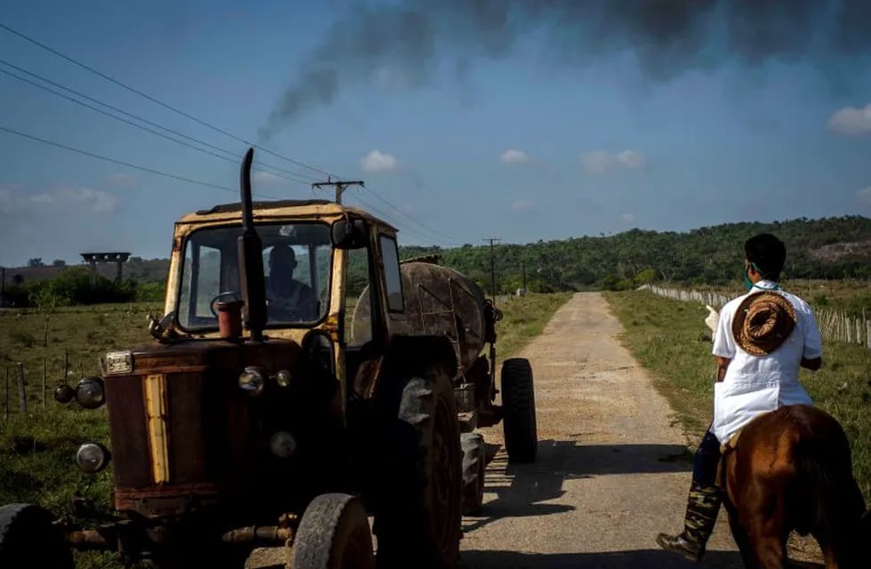 Medical student Hector Manuel Batista rides a horse past a tractor on a countryside road in search of residents infected with COVID-19, in San Jose de las Lajas, Cuba, Thursday, April 30, 2020. (AP Photo/Ramon Espinosa)