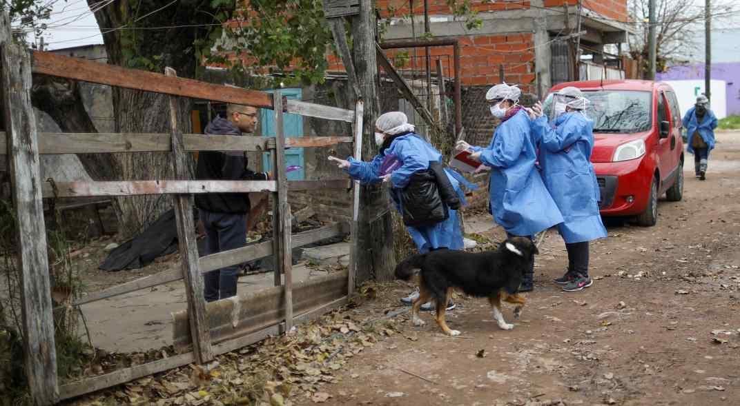 Trabajadores de la salud entrevistan a un residente fuera de su casa en el barrio Villa Azul, aislado por la cuarentena. (AP)