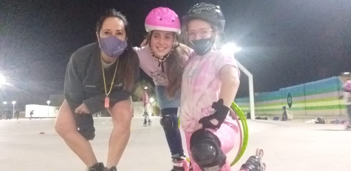 Docente con dos de sus pequeñas alumnas de carrera sobre patines.