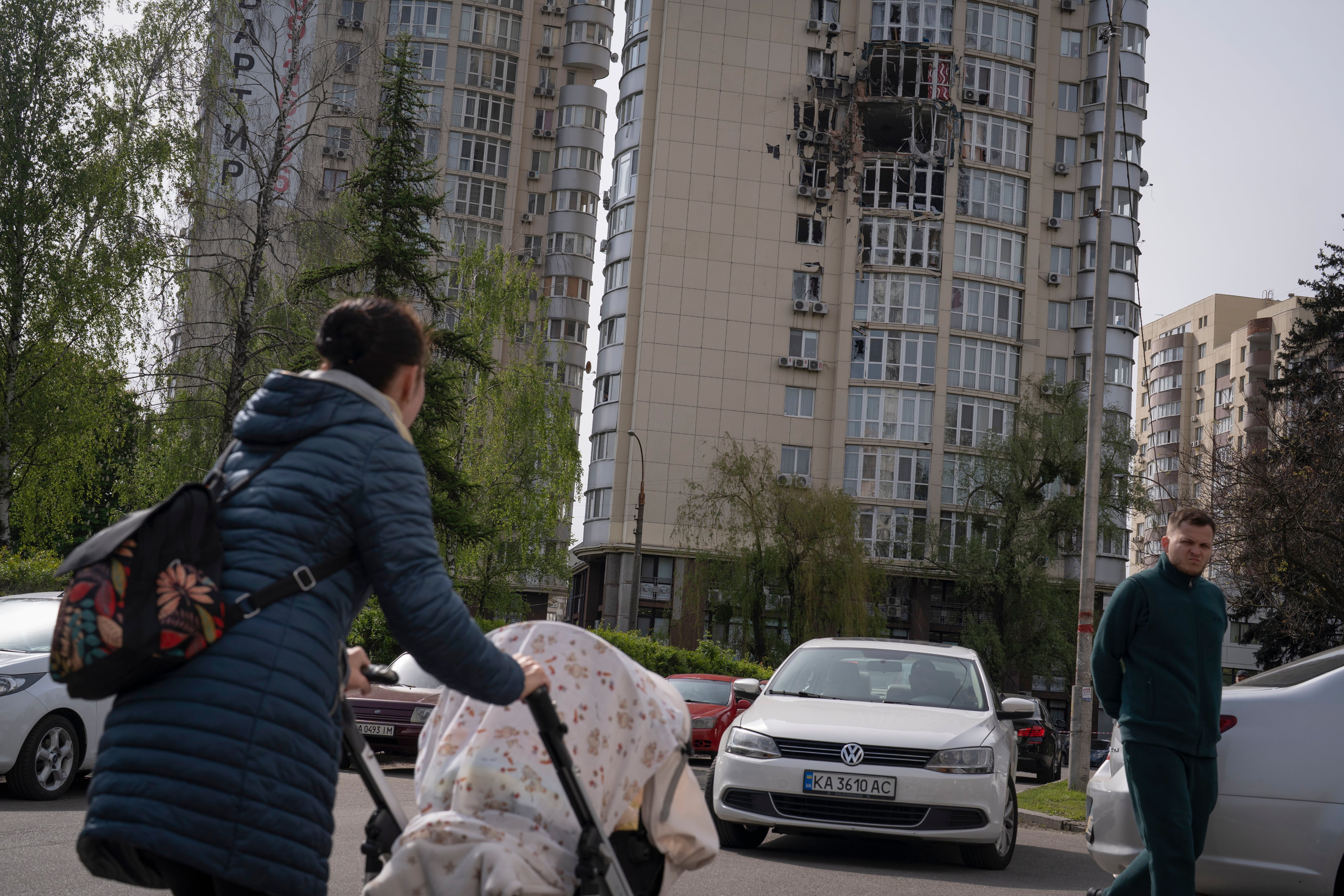 Gente pasa junto a un edificio de apartamentos dañado por restos de un dron derribado durante un ataque ruso por la noche. Los de este lunes, son las primeras ofensivas del Kremlin que se dan durante el día. Foto: AP / Andrew Kravchenko.