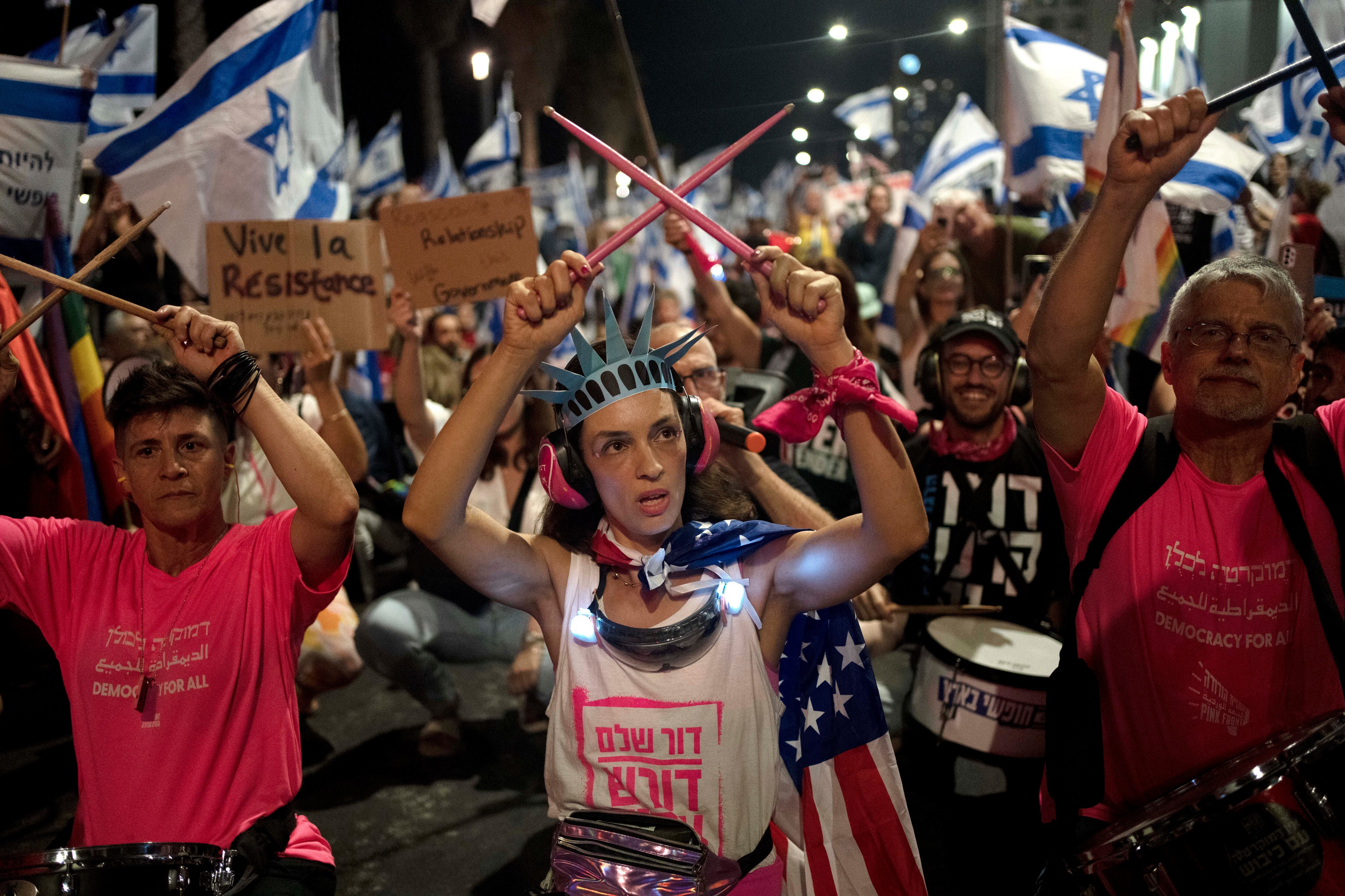 Una manifestante porta una corona como la de Estatua de la Libertad y una bandera estadounidense durante una protesta contra los planes del primer ministro israelí Benjamin Netanyahu para reformar el sistema judicial de la nación, frente a la oficina de la embajada de Estados Unidos en Tel Aviv, el jueves 13 de julio de 2023. Foto: AP / Maya Alleruzzo.