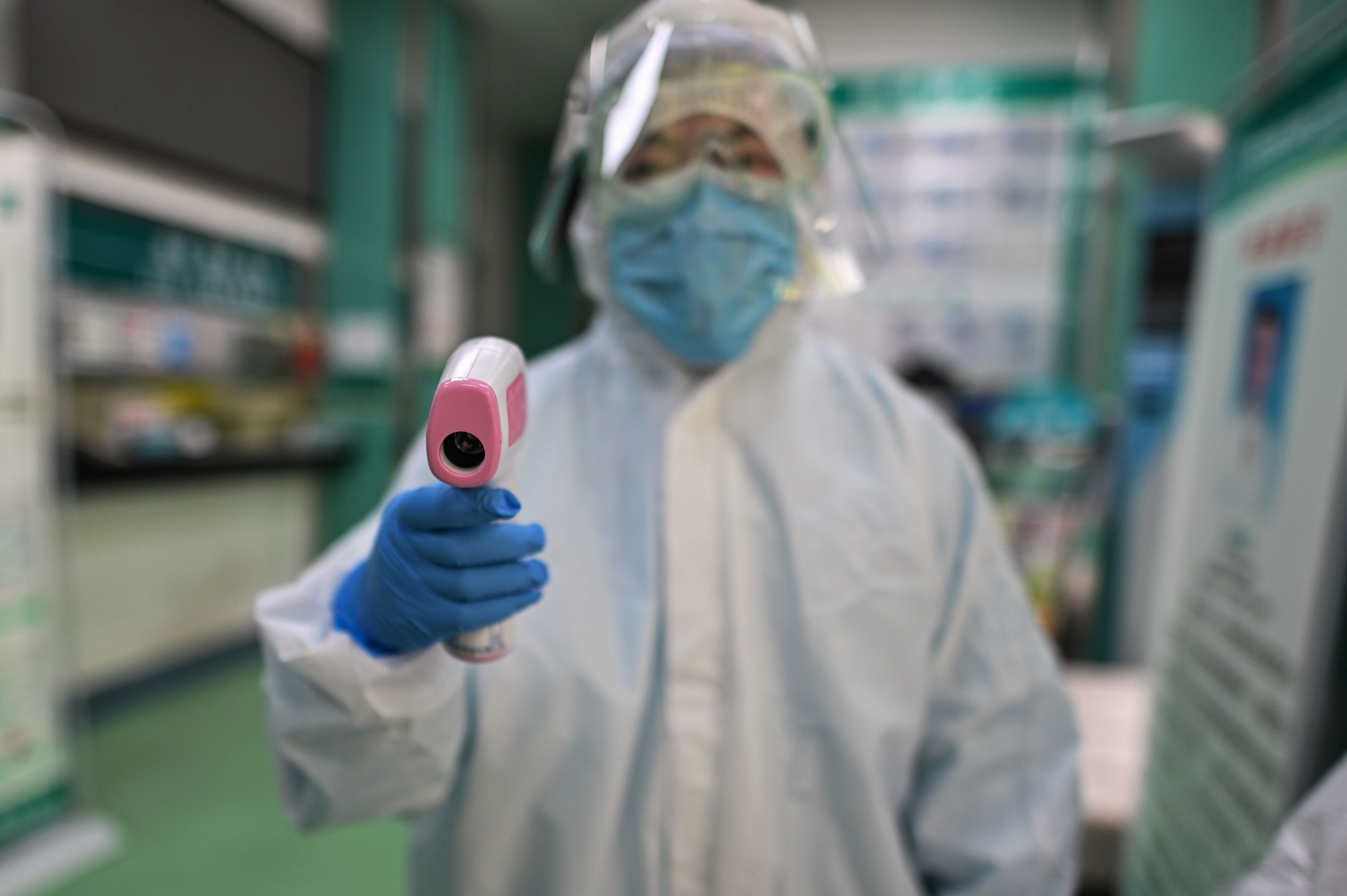  Un trabajador médico se prepara para tomar la temperatura de un reportero gráfico de AFP antes de una prueba de coronavirus COVID-19 en Wuhan. Hector Retamal/AFP