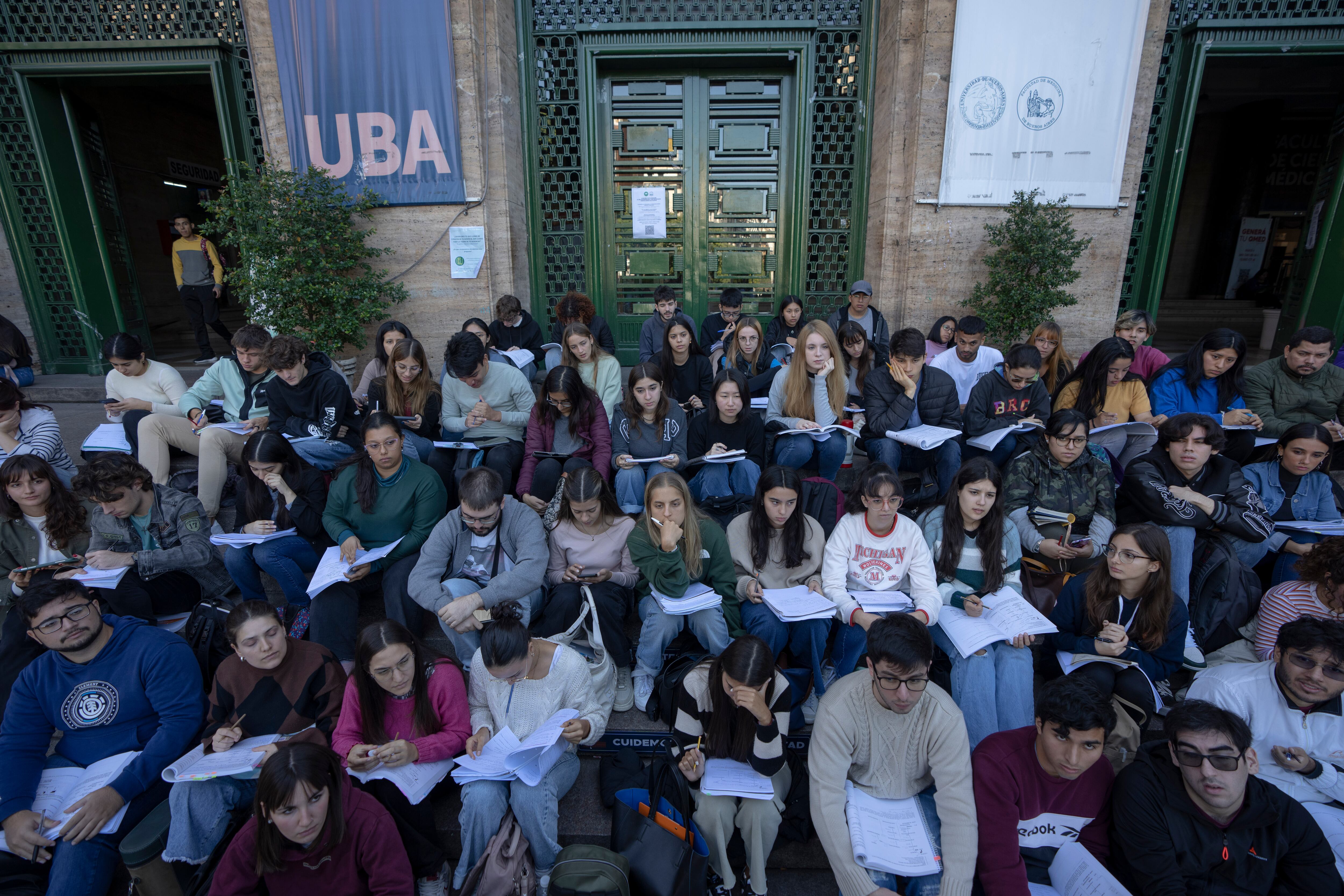 Estudiantes de la Universidad de Buenos Aires (UBA) toman clase en la calle en Buenos Aires, Argentina, el jueves 18 de abril de 2024. La UBA llevó al exterior las clases como protesta por el congelamiento de su presupuesto dispuesto por el presidente argentino, Javier Milei, como parte de sus medidas de austeridad. (AP Foto/Víctor R. Caivano)