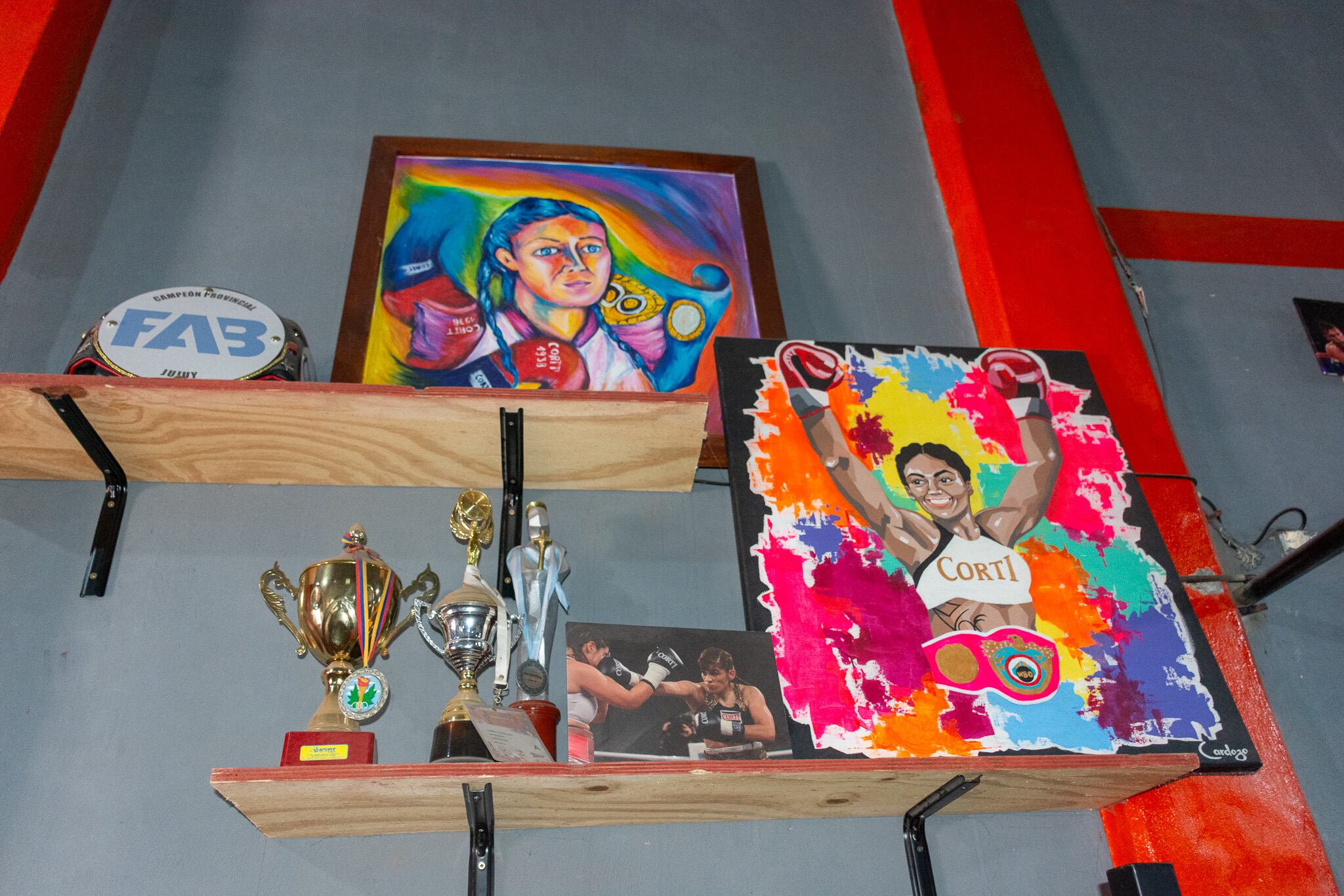 En exposición en la paredes del club: trofeos, retratos y una fotografía de "La Pumita" Carabajal y Marcela “Tigresa” Acuña en plena pelea, en el ring.