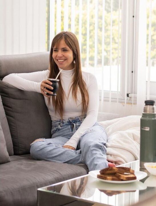 Romina Uhrig merendando desde el sillón de su casa