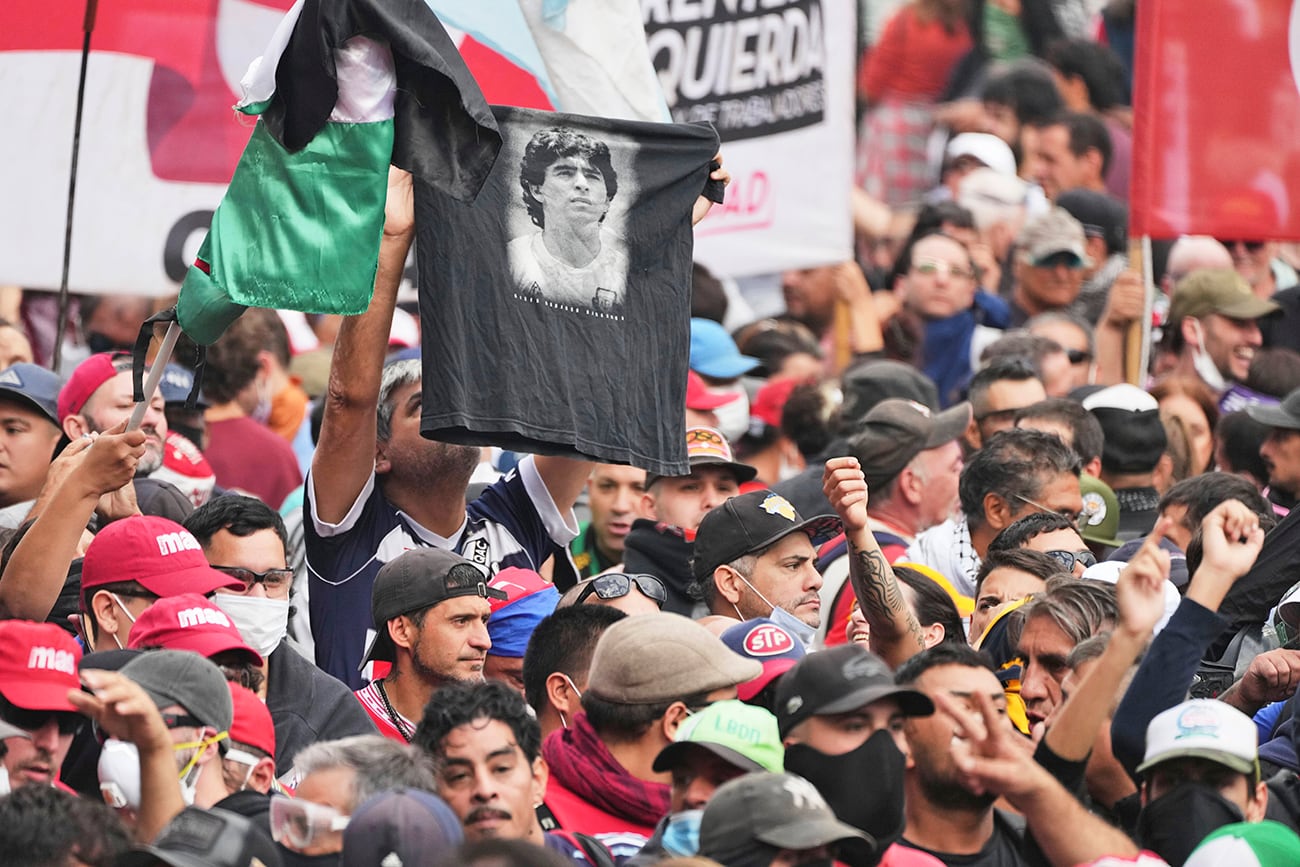 Un hincha sostiene una camiseta con una foto de Diego Maradona durante una protesta con jubilados. (AP)