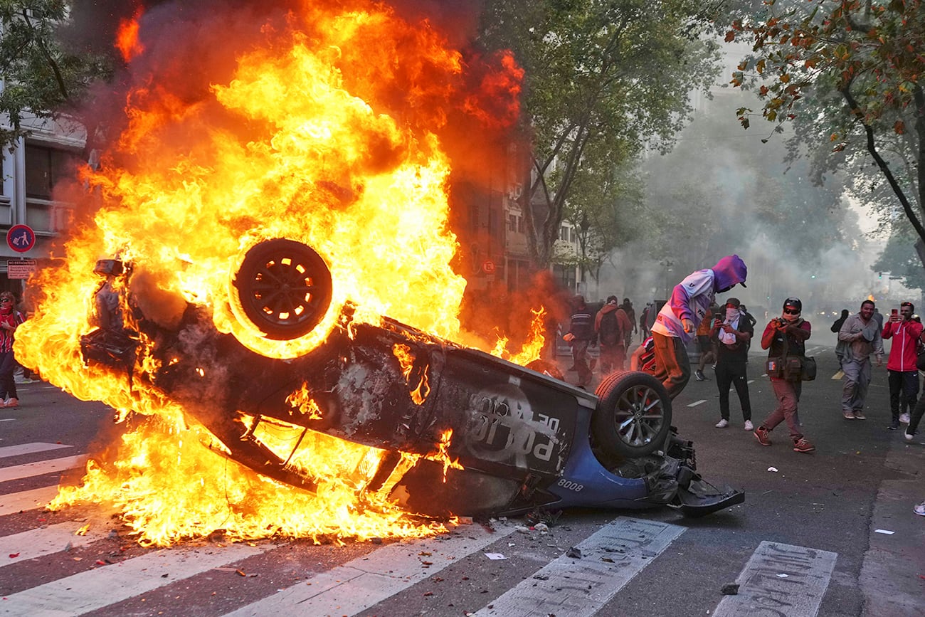 Un manifestante quema un patrullero durante la manifestación. (AP)