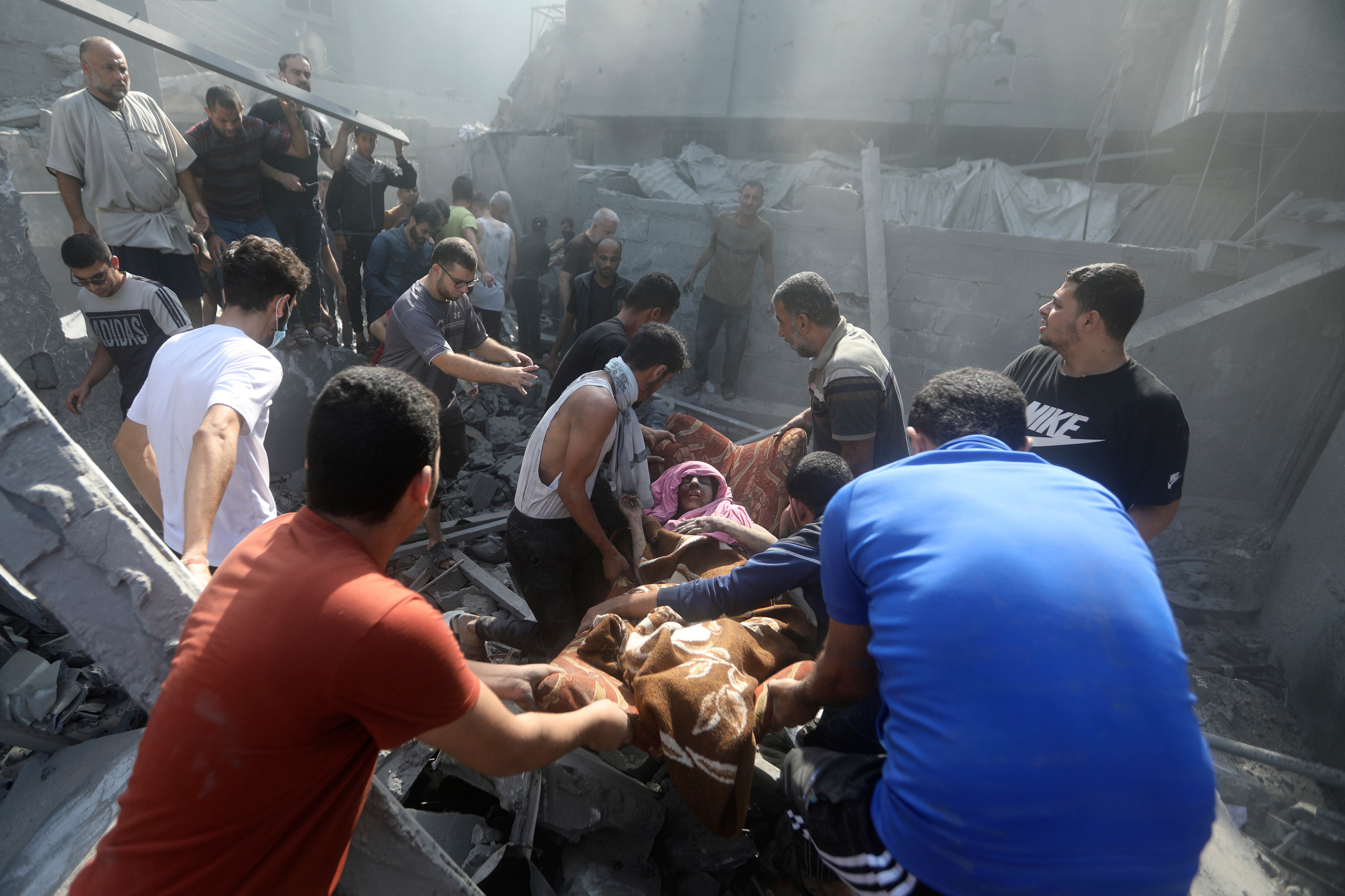 Palestinos trasladan a una mujer herida que fue rescatada de entre los escombros de un edificio destruido tras una ataque aéreo israelí sobre el campo de refugiados de Bureij, en la Franja de Gaza, el 2 de noviembre de 2023. 