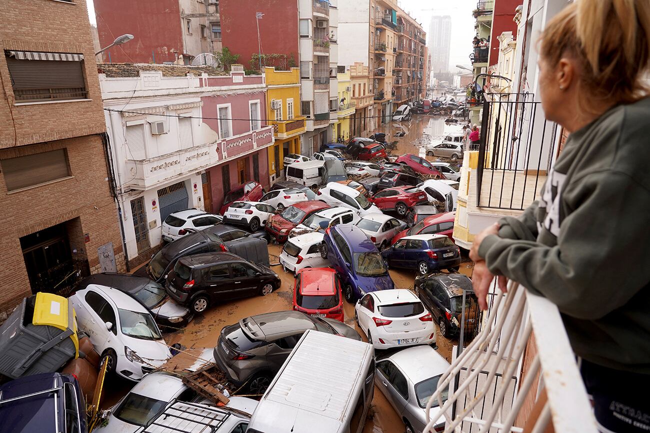 Una mujer mira desde su balcón mientras varios vehículos quedan atrapados en la calle tras las inundaciones en Valencia, el miércoles 30 de octubre de 2024. (Foto AP/Alberto Saiz)