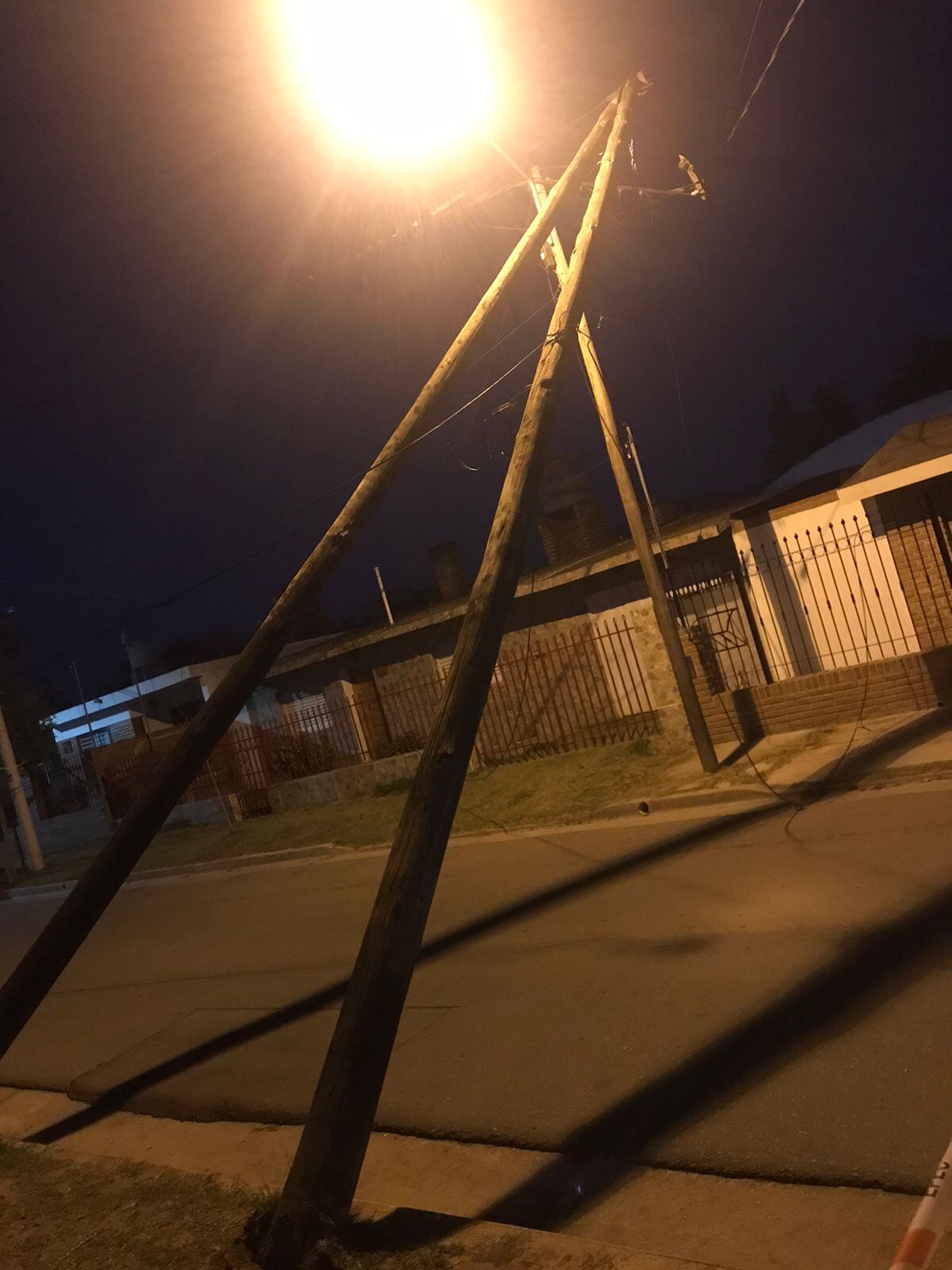 Dos postes de luz fueron volteados por el viento y quedaron sostenidos por cables.