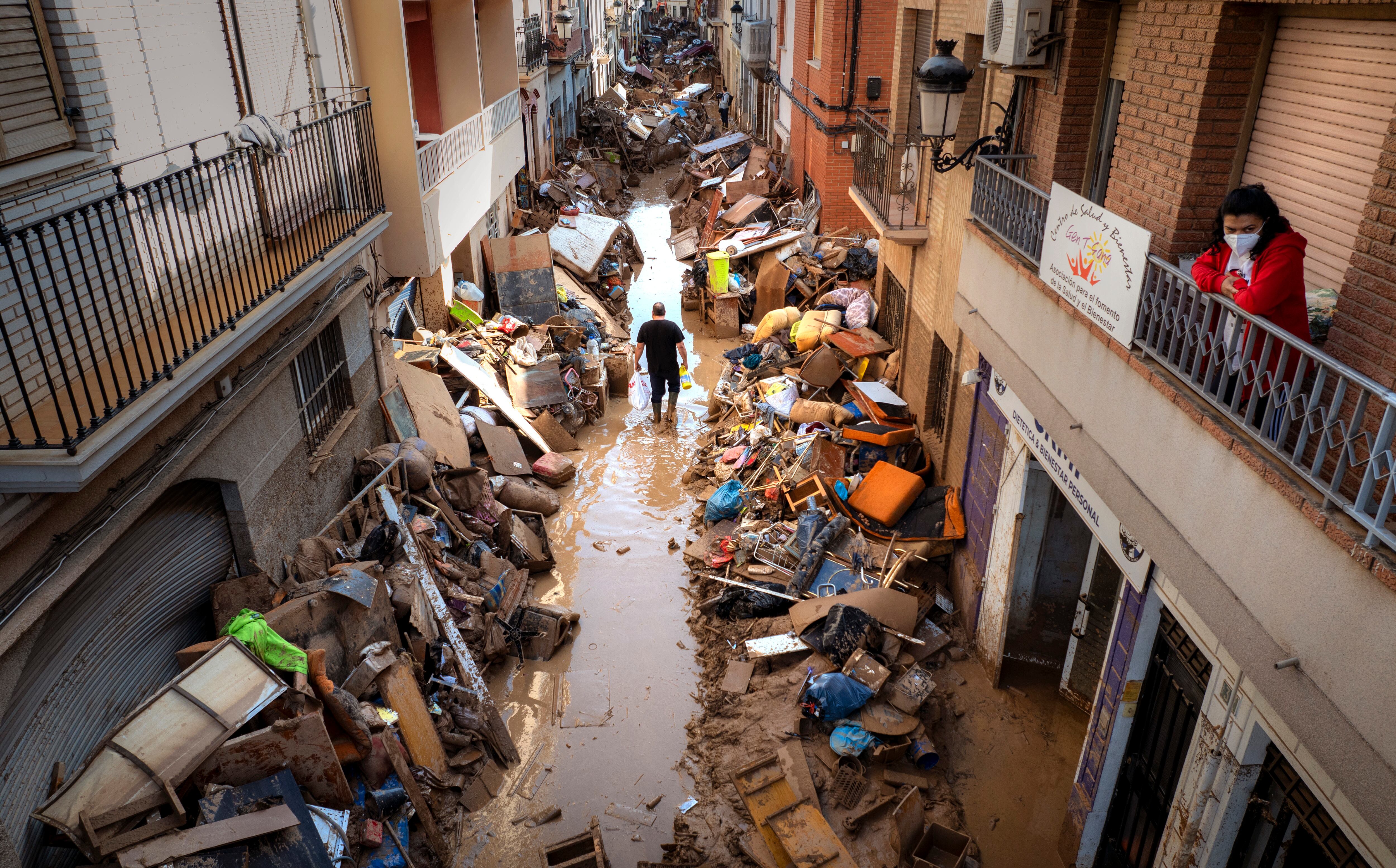 Varias personas caminan por una calle con muebles y escombros apilados. (AP Foto/Emilio Morenatti)