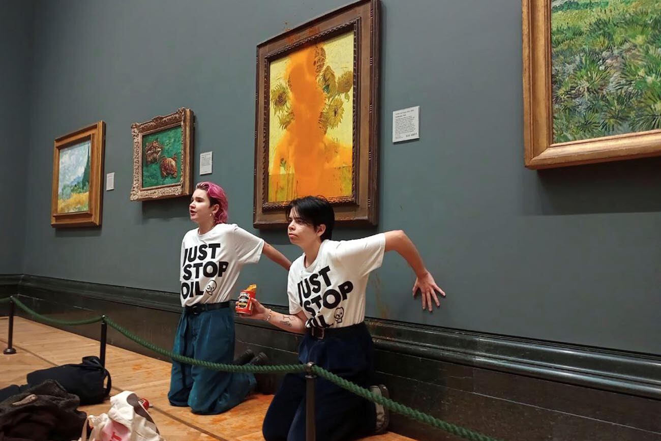 Foto del folleto emitida por Just Stop Oil de dos manifestantes que arrojaron sopa enlatada a la famosa obra Sunflowers de Vincent Van Gogh de 1888 en la Galería Nacional de Londres, el viernes 14 de octubre de 2022. El grupo Just Stop Oil, que quiere que el gobierno británico detenga nuevos proyectos de petróleo y gas, dijeron que los activistas arrojaron dos latas de sopa de tomate Heinz sobre la pintura al óleo el viernes. La Policía Metropolitana de Londres dijo que los oficiales arrestaron a dos personas bajo sospecha de daños criminales y allanamiento de morada con agravantes. (Simplemente detenga el petróleo a través de AP)