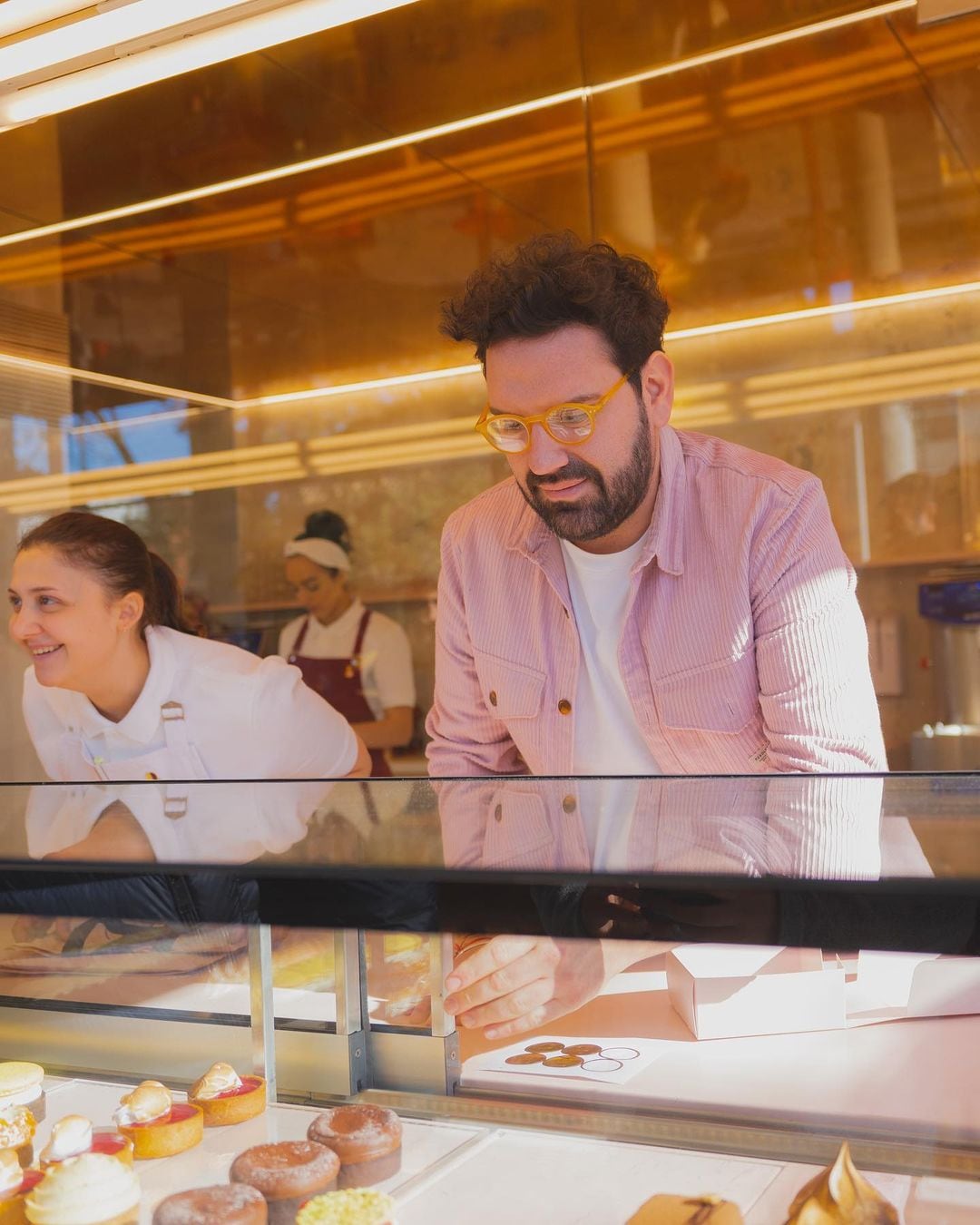 Damián Betular detrás del mostrador de su pastelería, tomando pedidos.