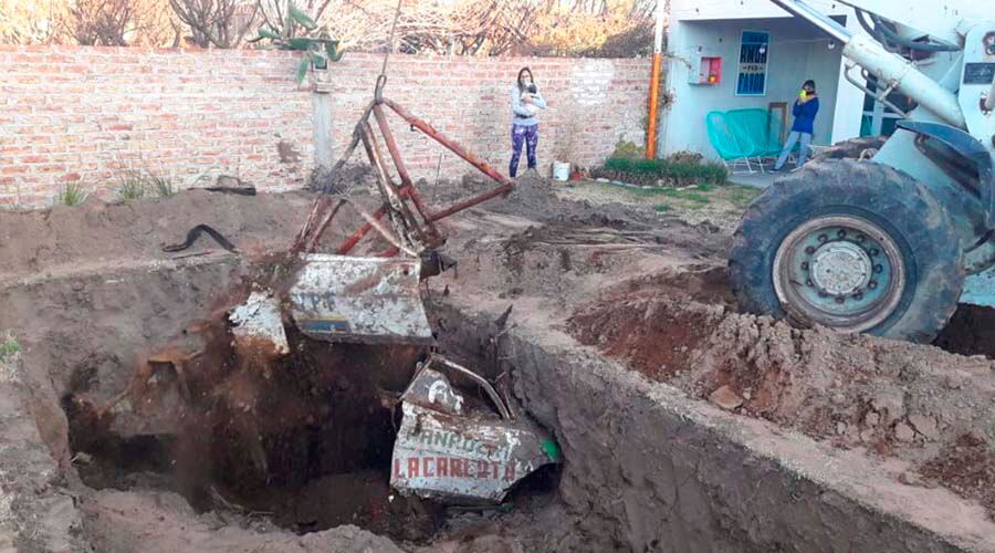 Una pala mecánica en la tarea de retirar los restos, con la dueña de casa observando 