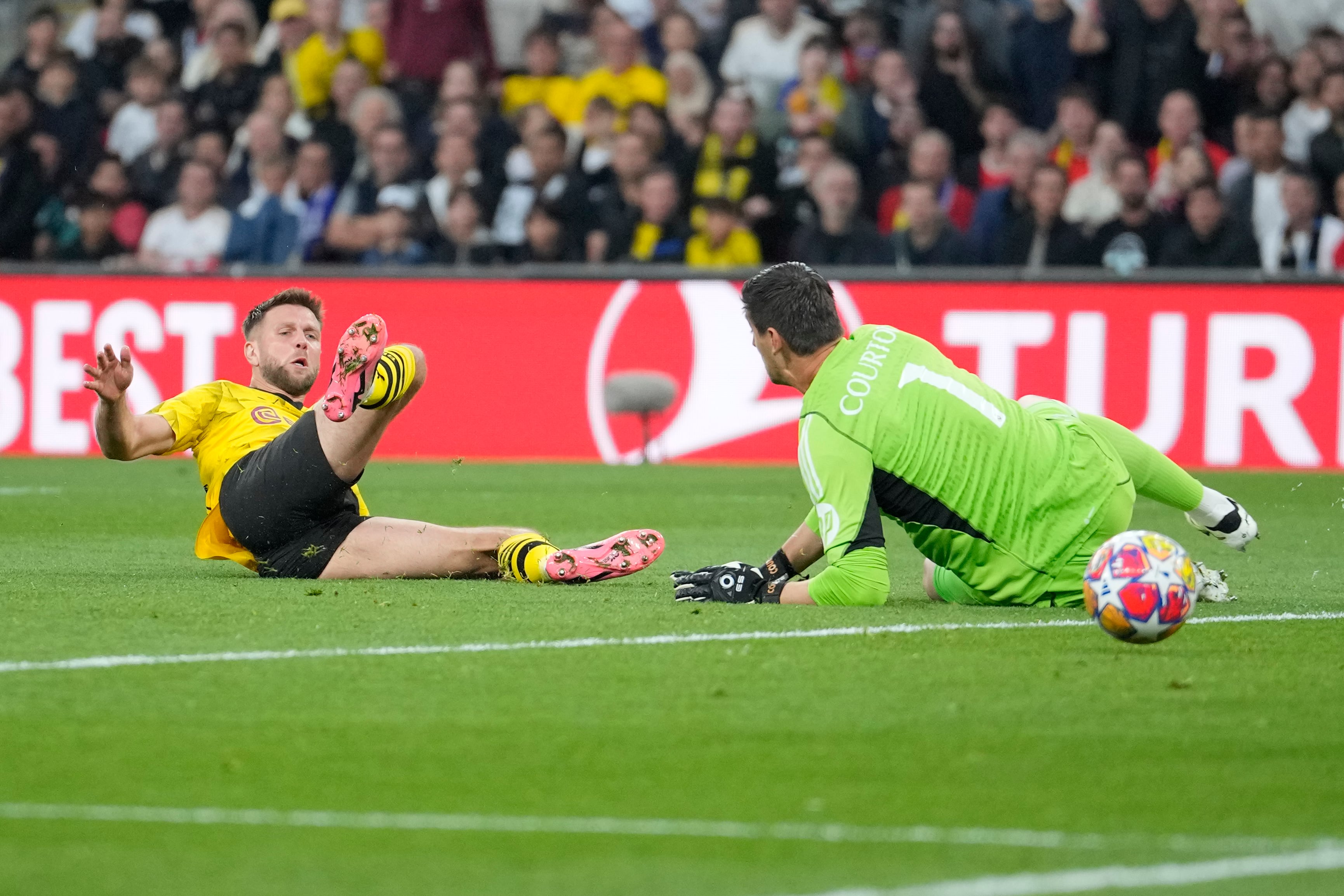 Niclas Fuellkrug (izquierda) del Borussia Dortmund remata ante el arquero Thibaut Courtois del Real Madrid durante la final de la Liga de Campeones, el sábado 1 de junio de 2024, en Londres. (AP Foto/Kin Cheung)