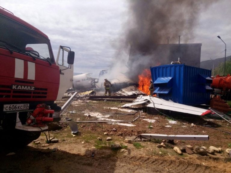 Los bomberos tratan de apagar las llamas tras estrellarse un avión de pasajeros en Nizhneangarsk, Rusia (EFE)